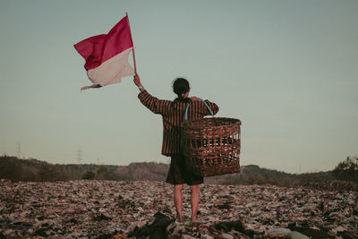 Rear view of man standing on land against clear sky