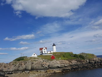 Lighthouse by sea against buildings