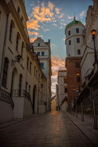Street amidst buildings in city at sunset