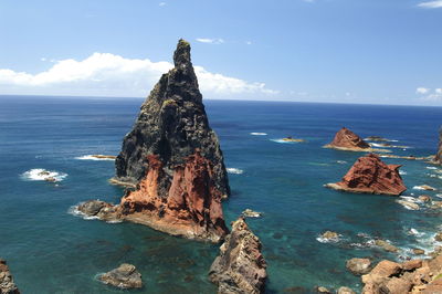 Rock formation by sea against blue sky