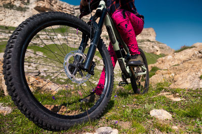 Close up of extreme mountain biking, cyclist riding off-piste in green field with mountains in