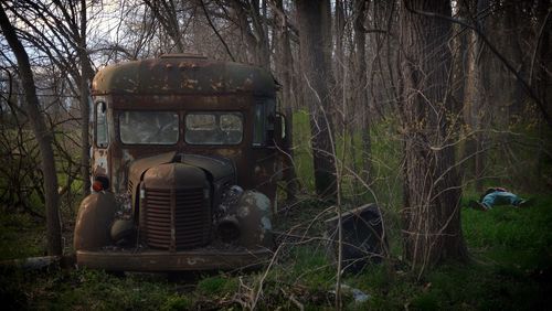 Man resting on grassy field by damaged car