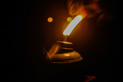 Close-up of burning candle over black background