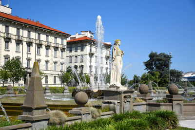 Statue by historic building against sky