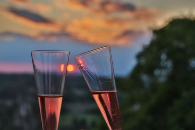 Close-up of beer glass against orange sky