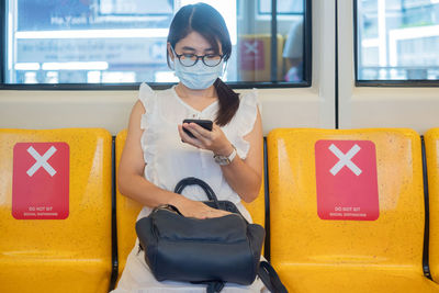 Close-up of woman using mobile phone at subway train