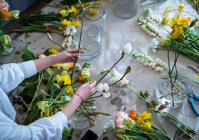 Women hands make bouquet at flower workshop with magnolia branches