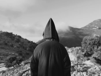 Rear view of man standing on mountain against sky