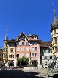 Buildings in city against clear blue sky