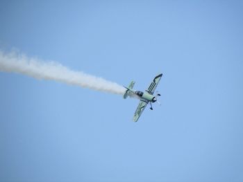 Low angle view of airplane flying against clear blue sky