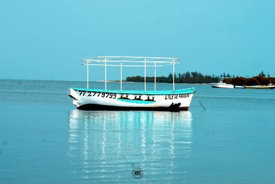 Boat moored in sea against clear blue sky