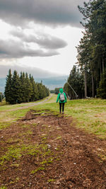 Rear view of man walking on land against sky