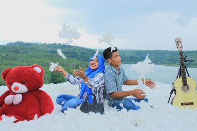 Rear view of men sitting on toy car against sky during winter