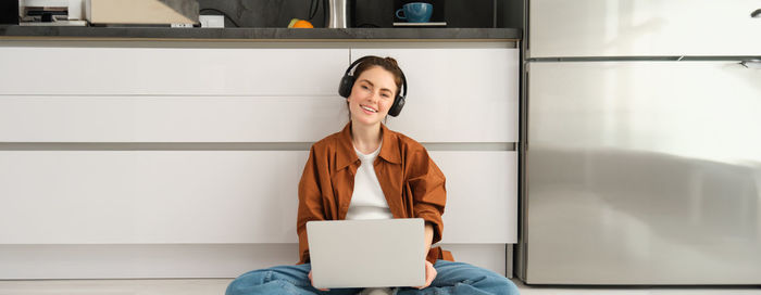 Portrait of young woman using mobile phone while standing at home