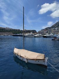 Sailboats moored on sea by city against sky