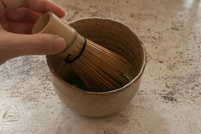 Cropped hand of holding mortar and pestle on table