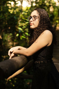 Young woman standing against trees