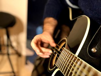 Midsection of man playing guitar