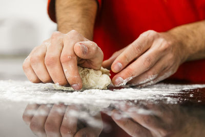 Midsection of man kneading dough at kitchen