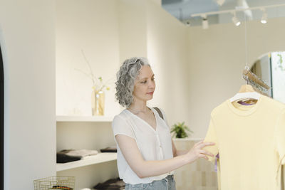 Woman choosing clothes hanging on rack at store