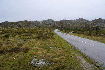 Road leading towards mountains against sky