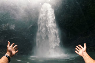 Midsection of person against waterfall