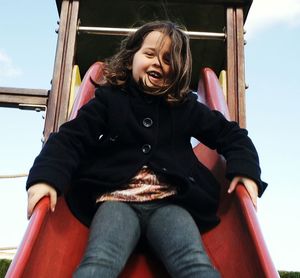 Low angle view of happy girl on slide in park