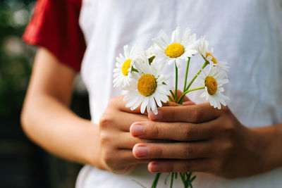 Holding a bouquet of daisies