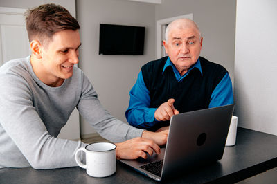 Grandfather and grandson using laptop at home