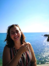 Portrait of smiling young woman against sea