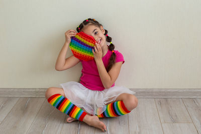 A cheerful little brunette girl , holding a rainbow pop it in her hands.