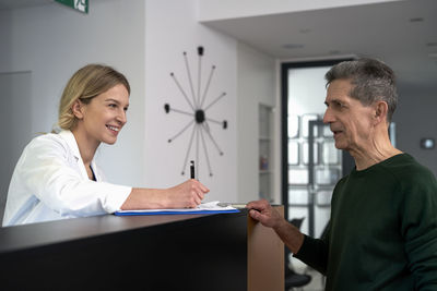 Smiling doctor registering patient at reception