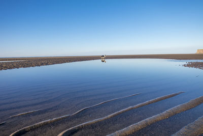 Scenic view of lake against clear blue sky