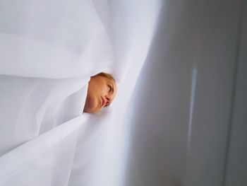 Low angle view of woman amidst white curtain