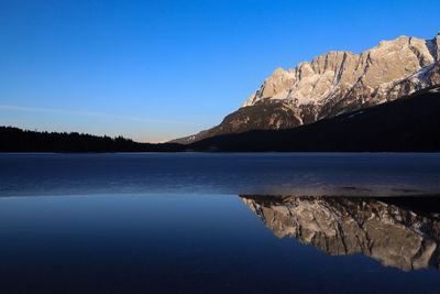 Scenic view of lake and mountains against clear blue sky