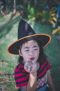 Girl wearing witch hat holding crystal ball