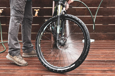 Low section of man standing on bicycle against wall