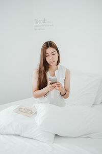 Young woman using mobile phone on bed