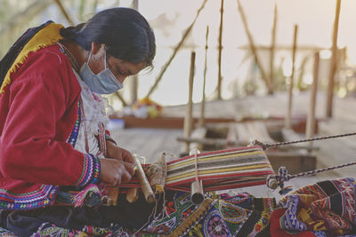 Indigenous woman showing traditional weaving technique and textile making in the andes mountain