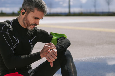 Man looking away while sitting on road
