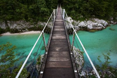 Footbridge over river amidst trees in forest