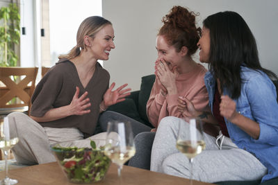 Smiling female friends eating food at home