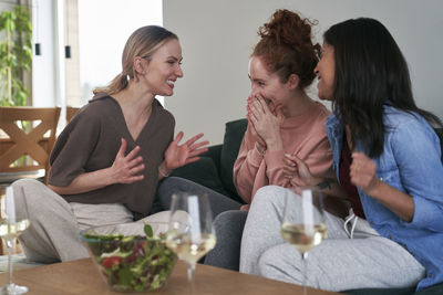 Female friends using mobile phone while sitting at home