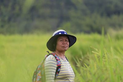 Portrait of mature backpack woman standing on field