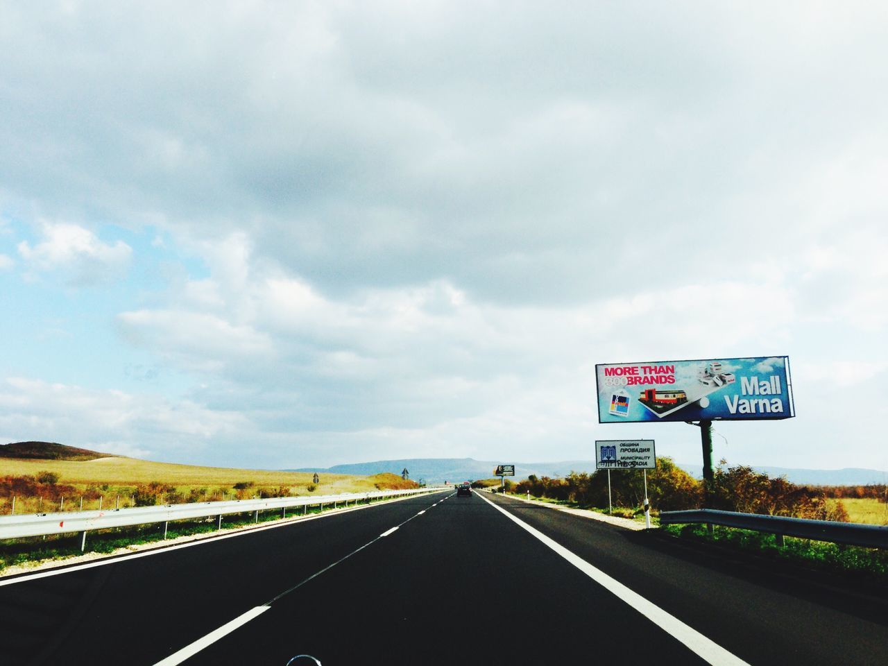 transportation, road, the way forward, road marking, sky, road sign, diminishing perspective, vanishing point, text, cloud - sky, communication, country road, western script, highway, guidance, cloud, dividing line, direction, arrow symbol, cloudy