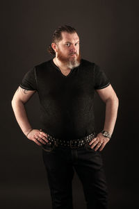 Portrait of young man standing against black background