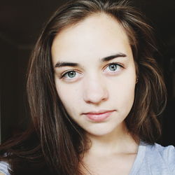 Portrait of young woman against black background