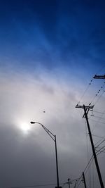 Low angle view of silhouette birds on electricity pylon against sky