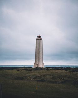 Lighthouse on field against sky