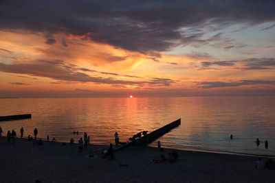 People on beach against sky during sunset